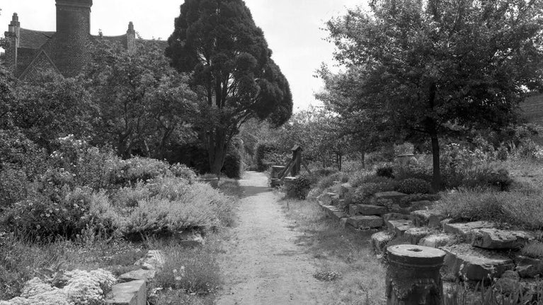 A black and white image of a garden path and stacked stone slabs on the right hand side